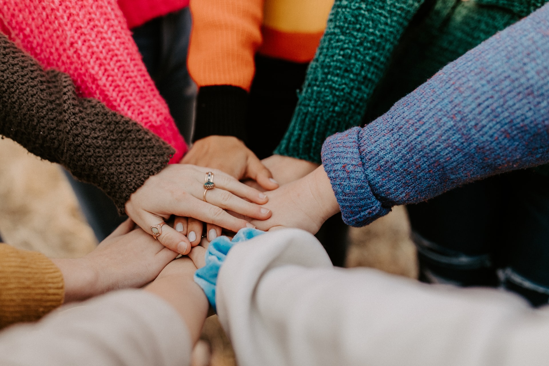 A close up of womens hands onto of each other in solidarity.